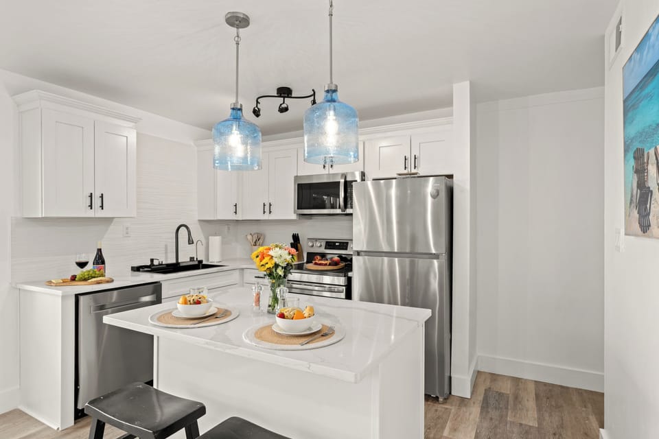 Fully updated kitchen equipped with a central prep island, pristine quartz countertops, and stainless steel appliances.