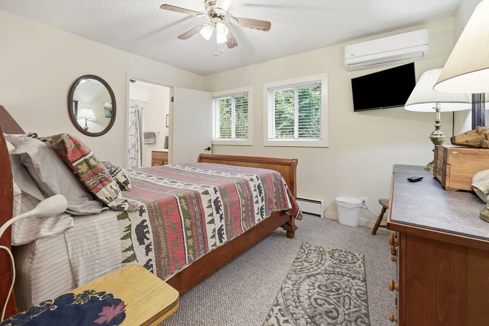 Bedroom with a wooden bed, wall-mounted TV, and attached bathroom.