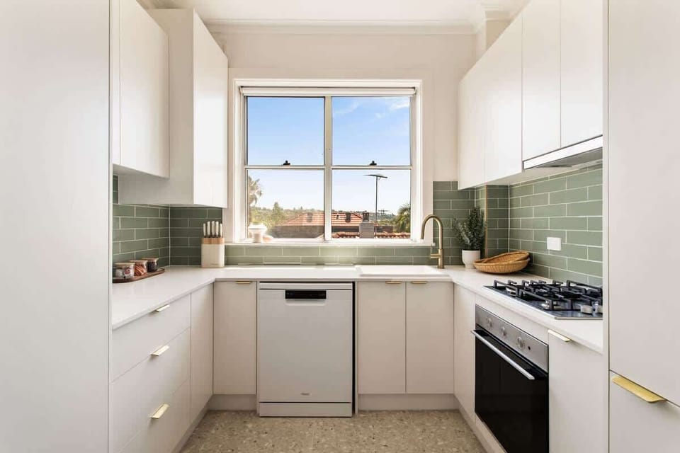Kitchen: Bright and airy, featuring sleek cabinetry and stunning green tile! Cook up a storm!