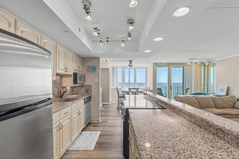 Cook with a view! This bright, fully equipped kitchen looks straight out toward the living area and the ocean beyond.