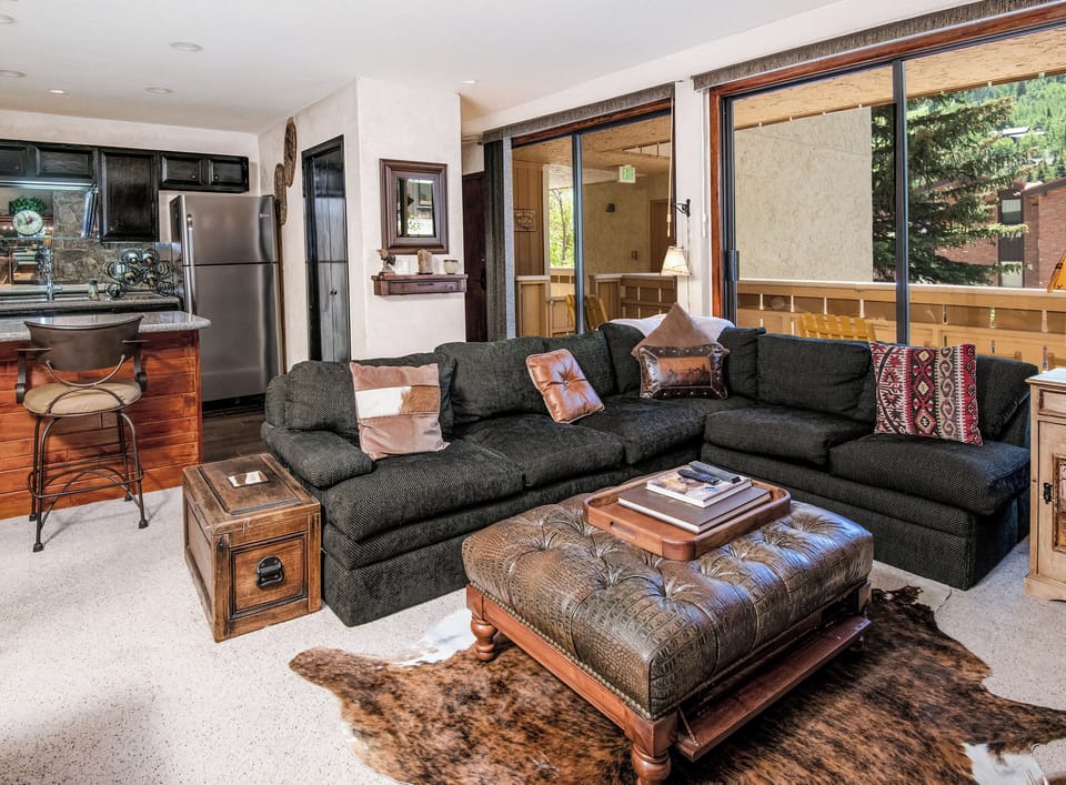 Settle into your inviting living space where a plush sectional beckons you to unwind after mountain adventures, while the open kitchen and private balcony add to your home-away-from-home comfort.