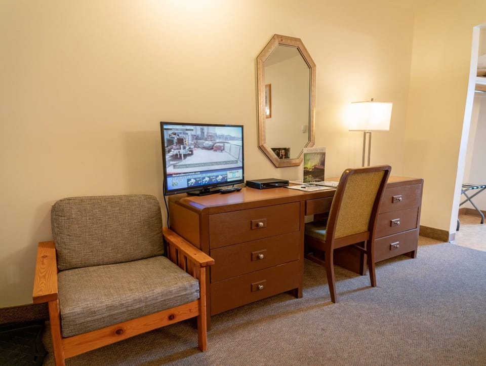 Flat-screen TV, writing desk, and wooden chair fill out the living corner of the room