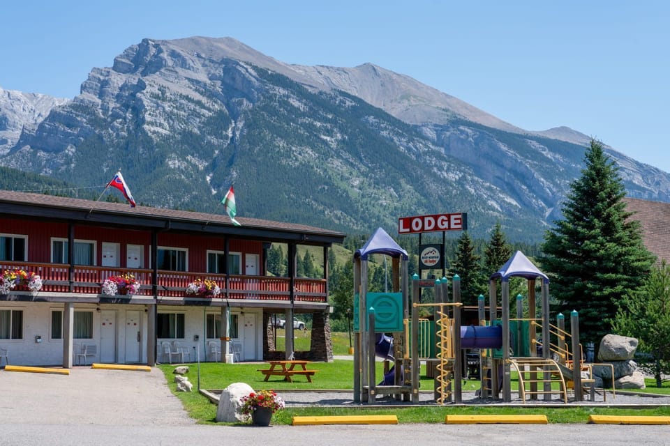 Outdoor common area with a kids' playground, set against the tree-lined mountain landscape
