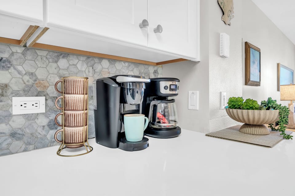 You'll love starting your mornings here with a perfectly brewed cup from the coffee station, set against elegant marble backsplash and bright white countertops.