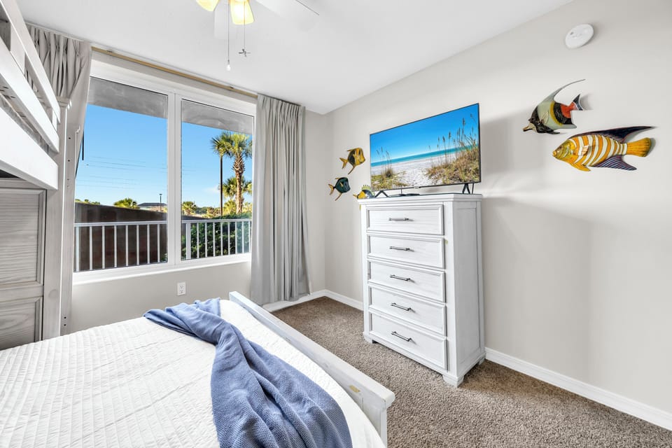 Drift off in your bright coastal bedroom, where palm views and playful fish art set a breezy, beachy vibe perfect for unwinding after a day in the sun.