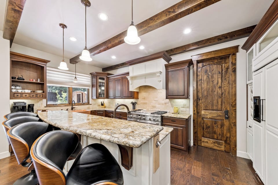 Gather around this stunning kitchen island where rustic wood beams and granite countertops blend to create your perfect cooking and entertaining space.