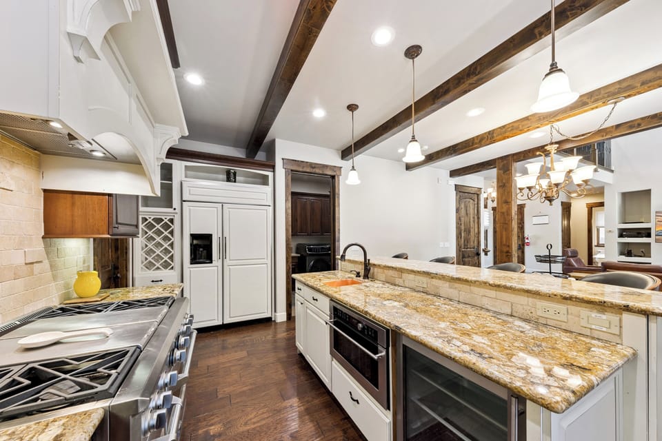 Step into your fully-equipped gourmet kitchen, where rustic beamed ceilings meet modern appliances and gleaming granite countertops invite you to craft memorable meals together.