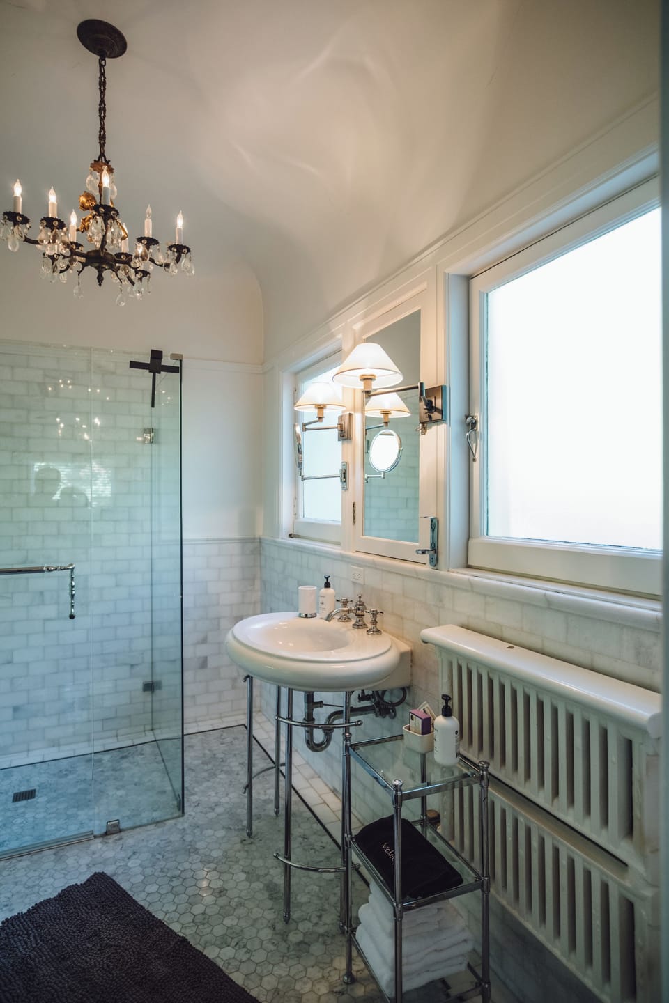 Elegant spa-like bathroom with chandelier and glass walk-in shower