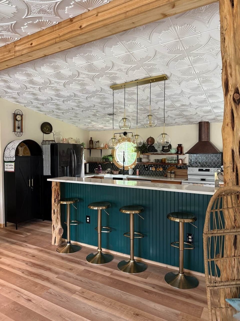 Gather at the cozy teal and gold kitchen island, where elegance meets earthly simplicity. Hand-oiled cedar wood accents—harvested from local trees—bring warmth and story to the space. Dimmable brass pendant lights add a whimsical, glow. 