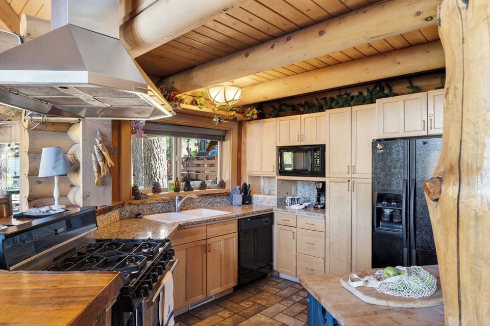 Rustic log cabin kitchen with live-edge bar seating, warm wood details, and easy flow into the dining area.
