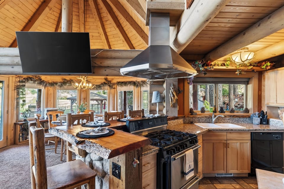 Rustic log cabin kitchen with live-edge bar seating, warm wood details, and easy flow into the dining area.