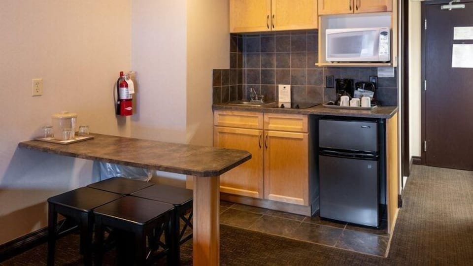 Kitchenette with oak cabinets, mini-fridge, microwave, coffee maker, and a four-seat breakfast bar