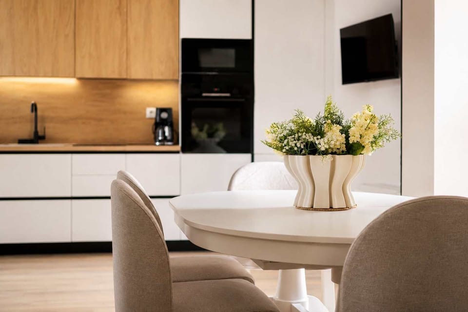 Another View of the Open Plan Living Room equipped with a sleek dining table, seating space and a Smart Tv that connects directly to the kitchen