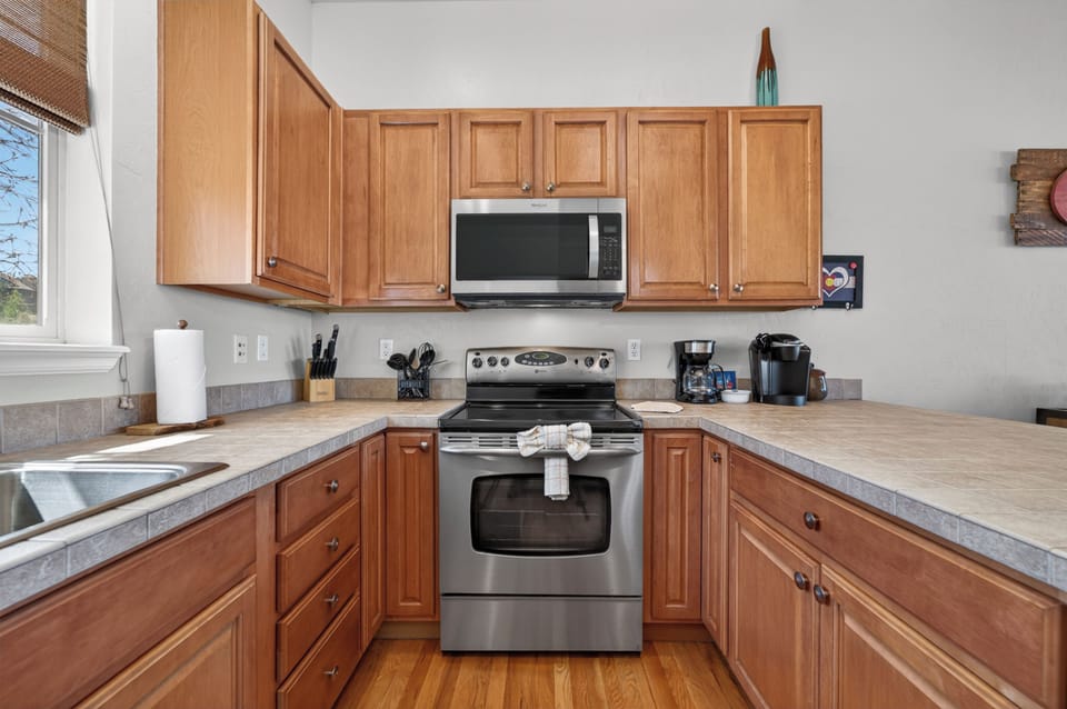 Your fully-equipped kitchen awaits with warm wood cabinets, stainless appliances, and ample counter space for preparing memorable meals during your stay.