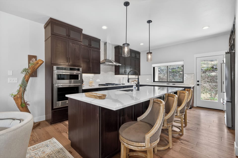 Cook your favorite meals in this open, sunlit kitchen with gleaming countertops and modern appliances, all centered around a spacious island perfect for gathering and sharing stories.