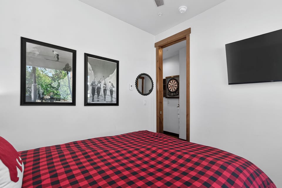 Your cozy bedroom features crisp white walls, vintage artwork, and a wall-mounted TV for relaxing evenings after exploring.