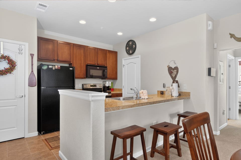 Your kitchen features warm wood cabinetry, modern appliances, and a cozy breakfast bar perfect for morning coffee or casual meals with family.