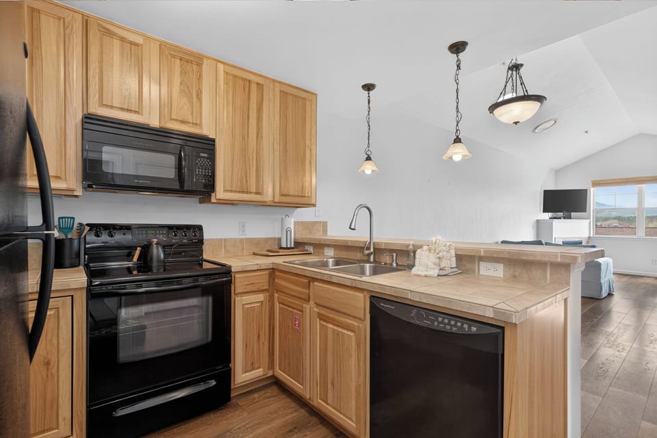 Modern kitchen ready for your culinary adventures, with full appliances, stylish pendant lighting, and an open layout flowing into your living space with scenic views.