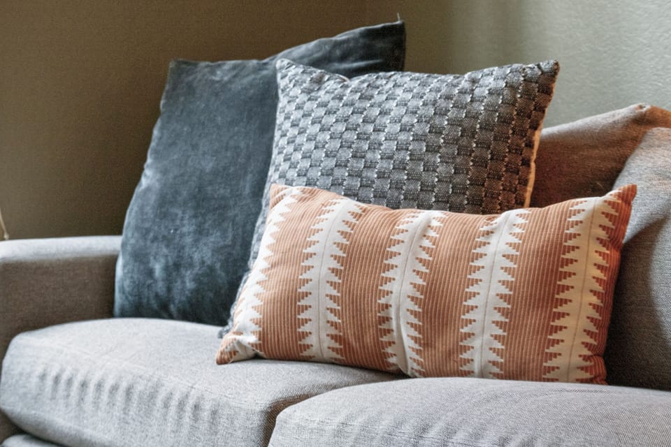 Sink into plush textures and calming tones—your living space awaits with layered pillows and a soft, welcoming sofa designed for ultimate comfort.