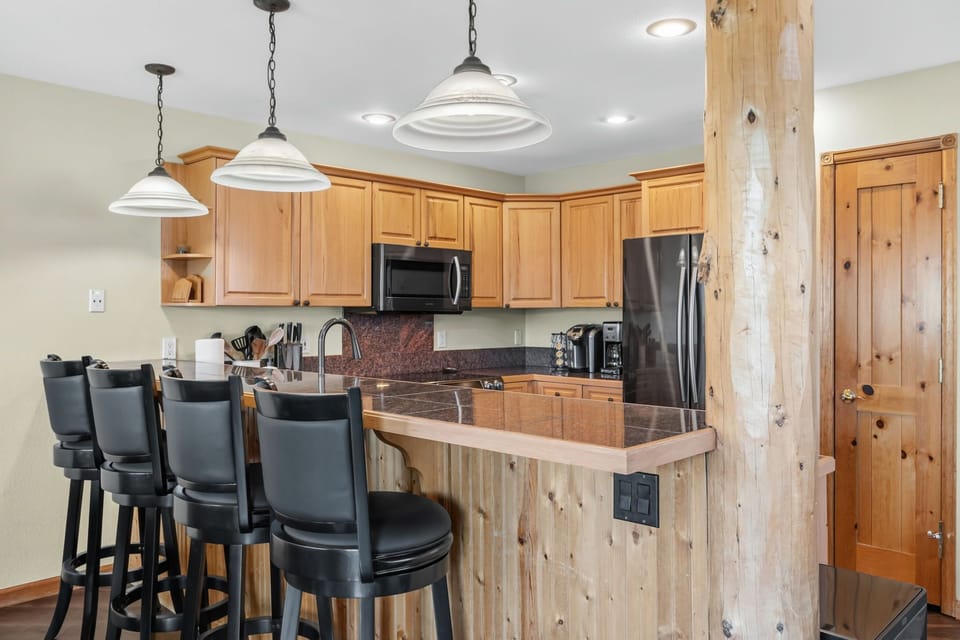 Gather around the breakfast bar where rustic wood meets modern convenience—your mornings here begin with fresh coffee and mountain views just outside the door.
