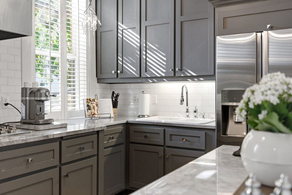 Cook your favorite meals in this beautifully appointed kitchen with sleek gray cabinetry, marble countertops, and stainless steel appliances that make every culinary moment a pleasure.