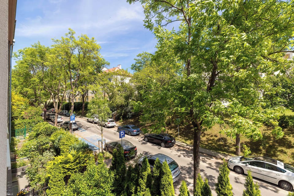 A leafy neighborhood view overlooks tree-lined streets and residential surroundings under clear skies. Greenery softens the urban setting.