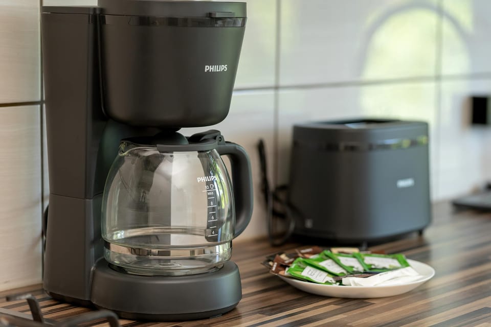 A close-up highlights a coffee machine and small kitchen accessories on the countertop. Compact appliances are neatly arranged for convenience.