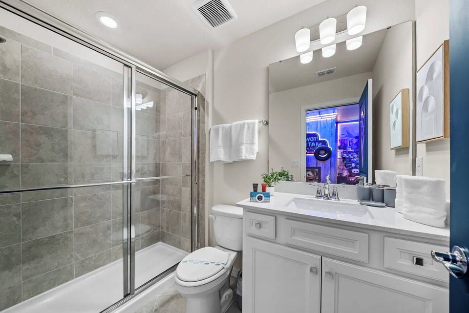 Experience comfort in this well-appointed bathroom featuring sleek glass shower doors and a spacious vanity. The soft lighting enhances the neutral tones, creating a clean and refreshing space for your relaxation.