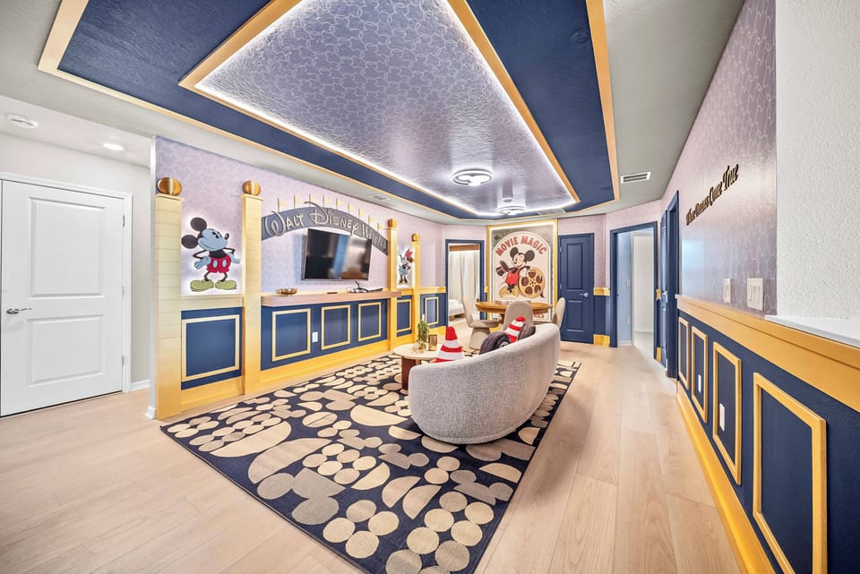Immerse yourself in a lively living area adorned with rich blue tones and golden accents. Unwind on the comfy sofa, feel the cozy warmth of the patterned rug, and enjoy the soft glow from the elegant ceiling lights.