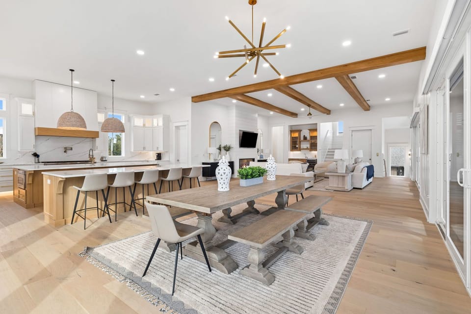 Your dream vacation retreat awaits in this stunning open-concept living space, where soaring ceilings with rustic wooden beams meet modern comfort—gather around the beautiful dining table or relax by the cozy fireplace.