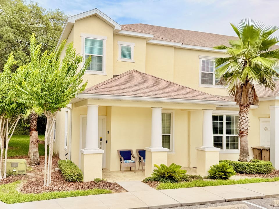 Tropical getaway! Multi-story home with front porch seating & lush palm trees.