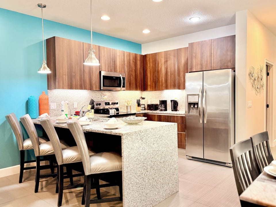 Sleek kitchen with granite island, modern appliances & a vibrant coffee station!