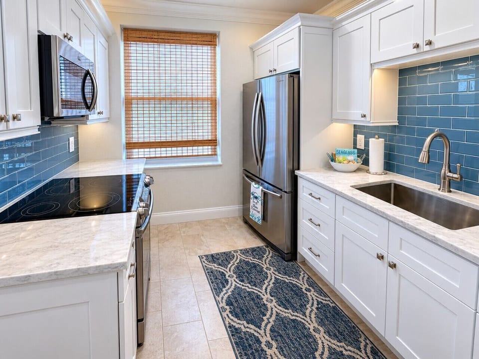 Fully renovated coastal kitchen with quartz countertops and stainless steel appliances.