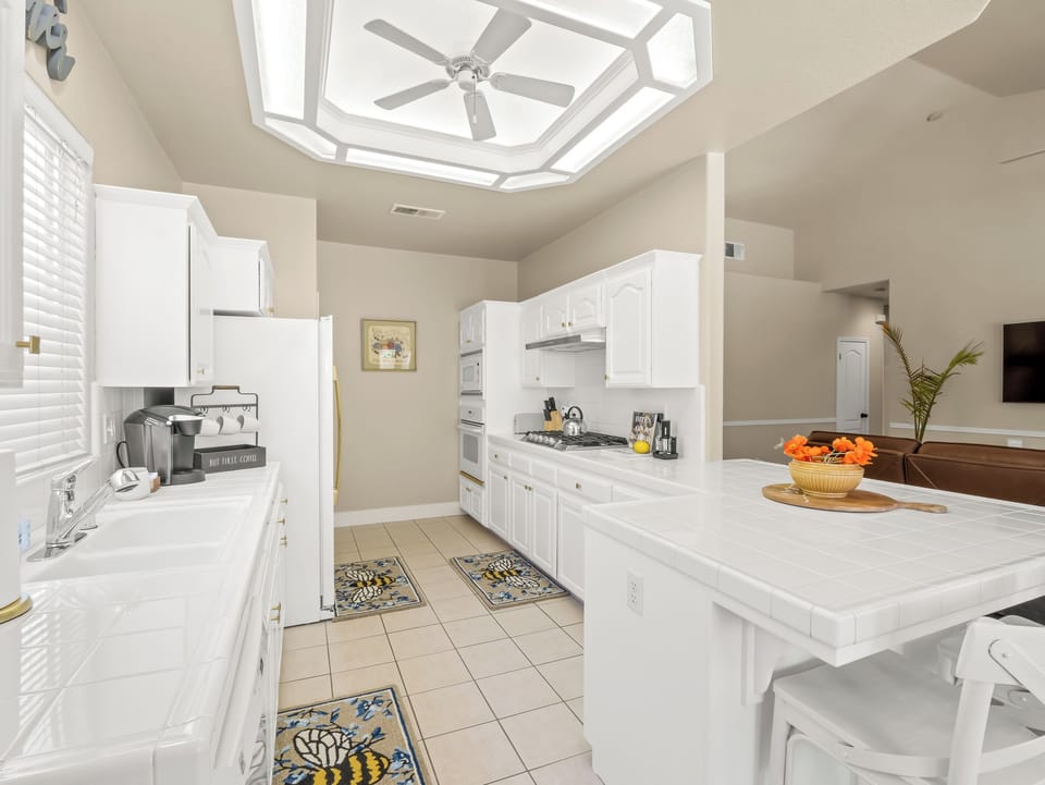 This spacious kitchen features ample cabinetry, extensive countertop space, full-size appliances, and a large island with seating.