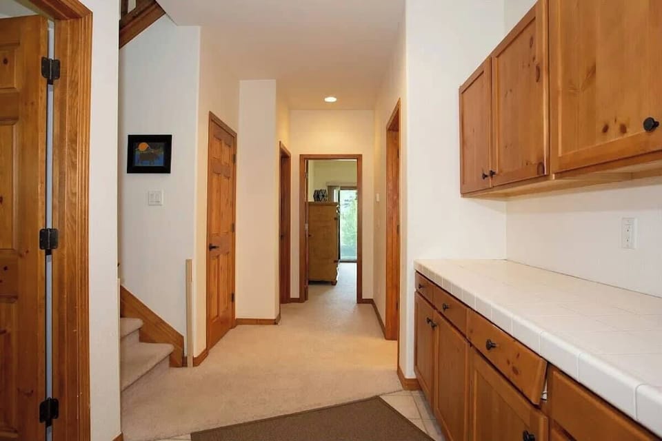 Entry hallway from the garage. From left looking clockwise, bedroom 4, stairs, under stair storage, bedroom 2, bedroom 3 and bathroom 3. Drop zone to the right and immediately to the right (not pictured) is laundry room with full-size washer & dryer.