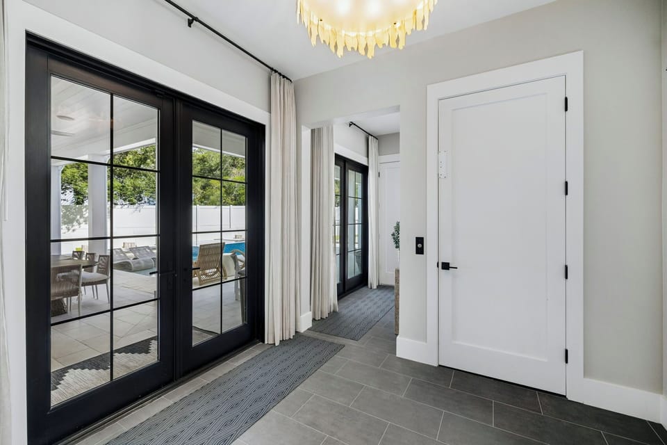 Step into a bright, welcoming entryway where natural light pours through elegant glass doors, inviting you straight out to your private patio and pool area—your vacation sanctuary awaits just beyond.