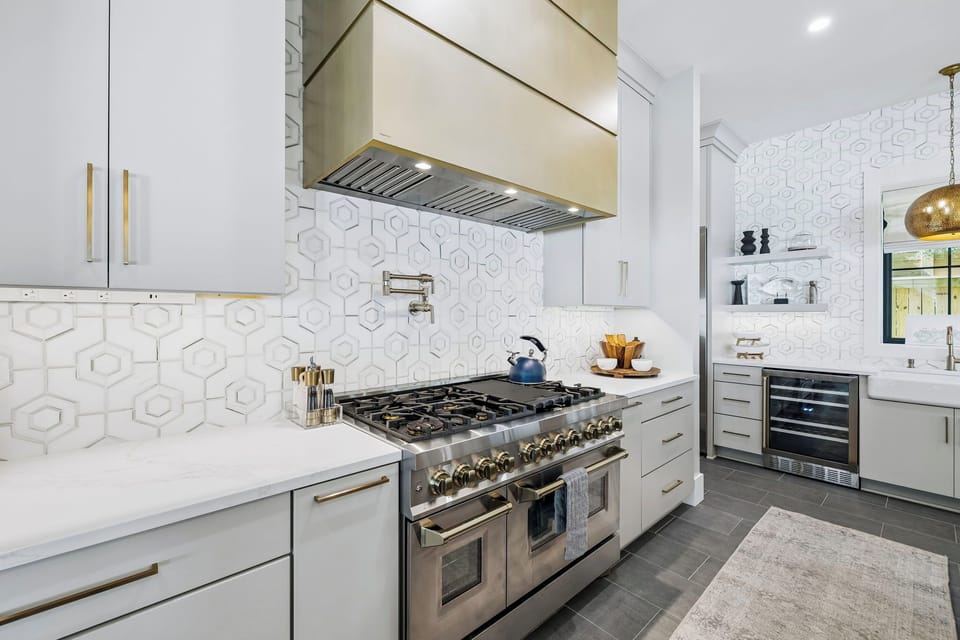 Your gourmet kitchen gleams with professional-grade appliances and designer details. Cook memorable meals on the dual-oven gas range beneath sleek ventilation, surrounded by pristine white cabinetry and elegant geometric tile.