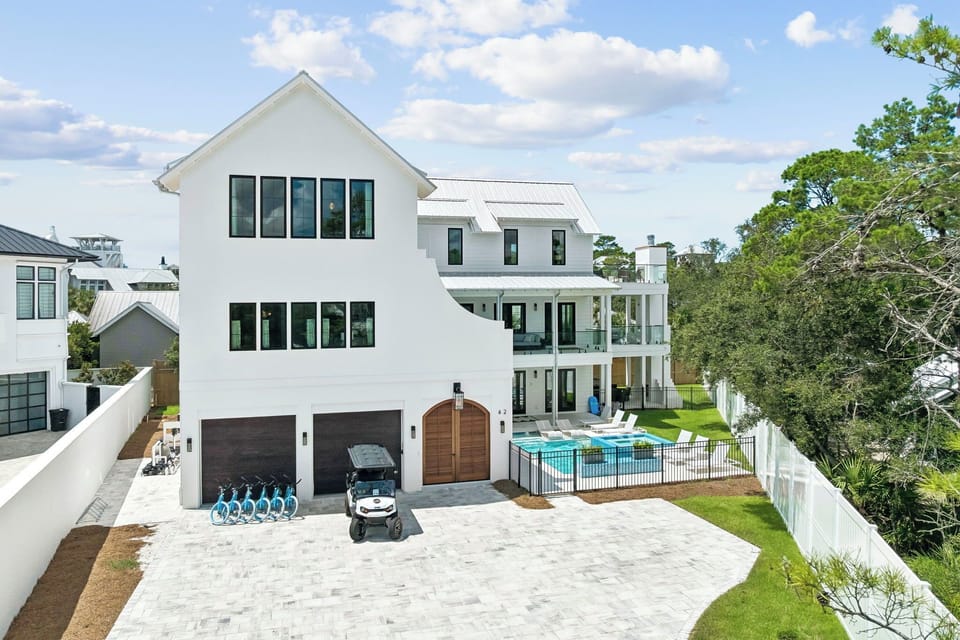 This stunning modern farmhouse features a private pool, spacious outdoor entertaining areas, and golf cart access—all set against a backdrop of natural greenery and coastal charm.