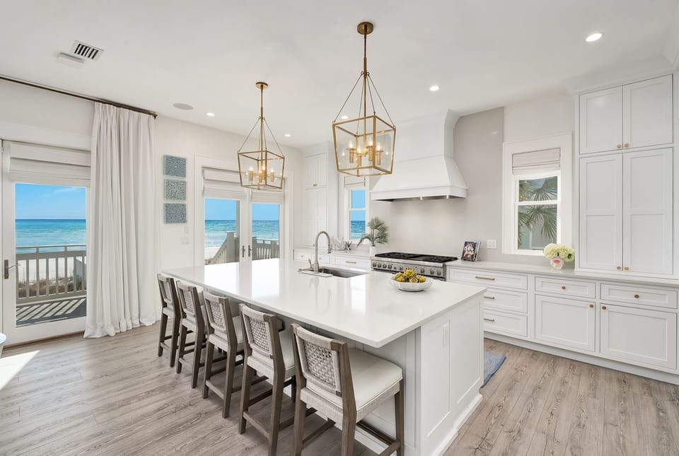 This bright, coastal kitchen opens onto a private deck overlooking the ocean. Picture yourself preparing meals at the spacious island while enjoying stunning sea views through large windows that fill the room with natural light.