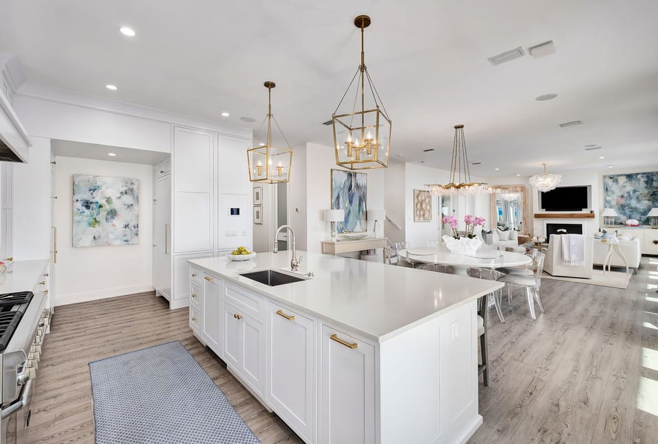 Elegant open-concept design flows seamlessly from your chef's kitchen into the bright living space, where gold-accented lighting and coastal artwork create a refined yet welcoming atmosphere for your stay.