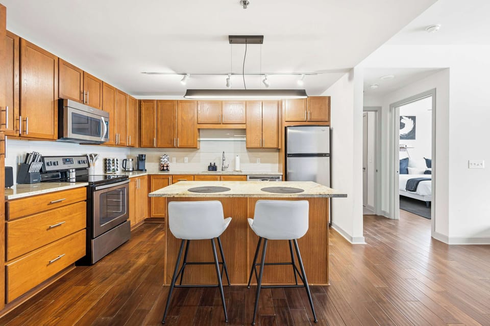 Kitchen and dining space with island counter seating, stainless appliances, and warm wood cabinetry.