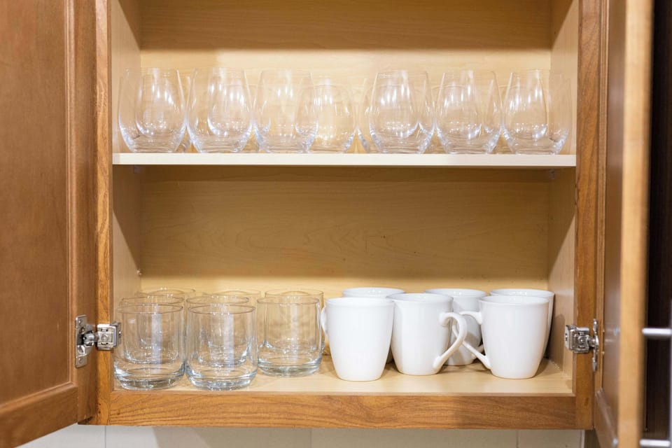 Cabinet stocked with wine glasses, mugs, and bowls ready for your stay.