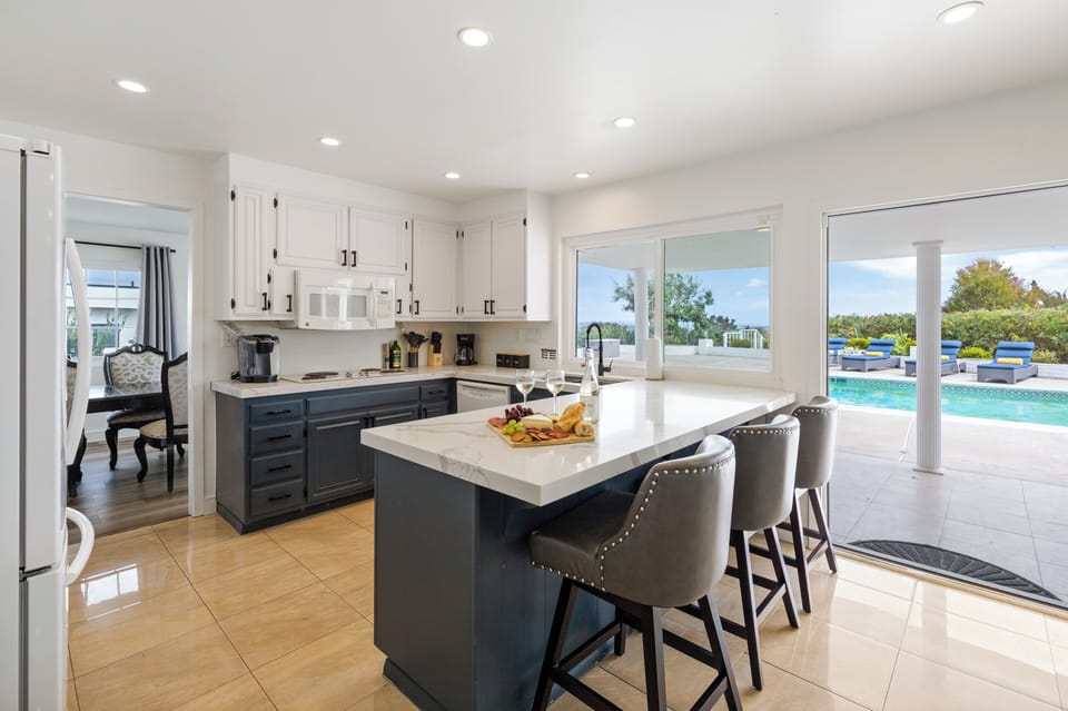 Bright kitchen with island seating, pool views, and easy indoor-outdoor flow for sunny California meals.