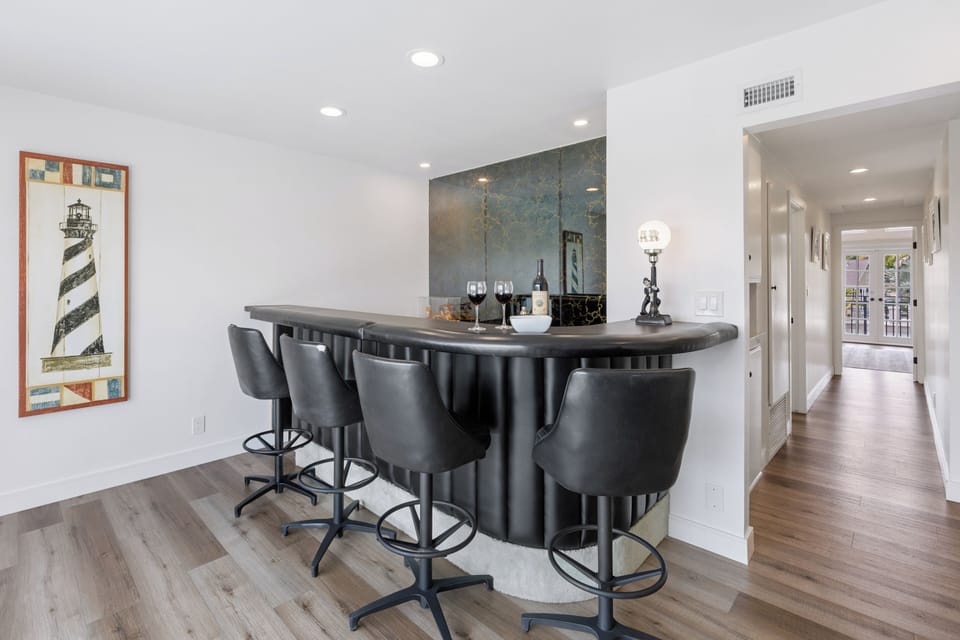 Private bar area with stylish seating, coastal artwork, and space for relaxed evening drinks.