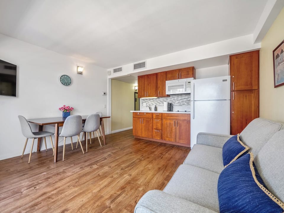 Living Area - Make yourself at home with a comfortable sofa, dining and workspace table, and compact kitchen together in one easygoing room. The practical layout supports simple meals and relaxed monthly living in Waikiki.