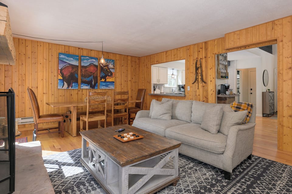 Unwind in your cozy living room at 1126 Western Road where rustic wood walls and a plush sofa create the perfect mountain retreat atmosphere.