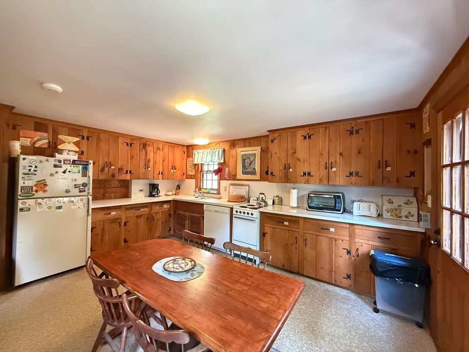 A warm, rustic kitchen invites you to gather and cook, with rich wood cabinetry, full appliances, and a welcoming dining table ready for shared meals and morning coffee.
