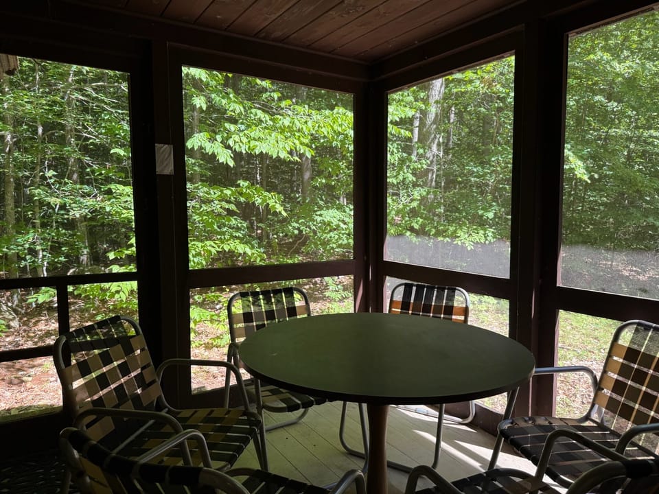 Your private screened porch overlooks tranquil woods, perfect for morning coffee or quiet evenings surrounded by nature. Relax in comfortable seating and breathe in the fresh forest air.