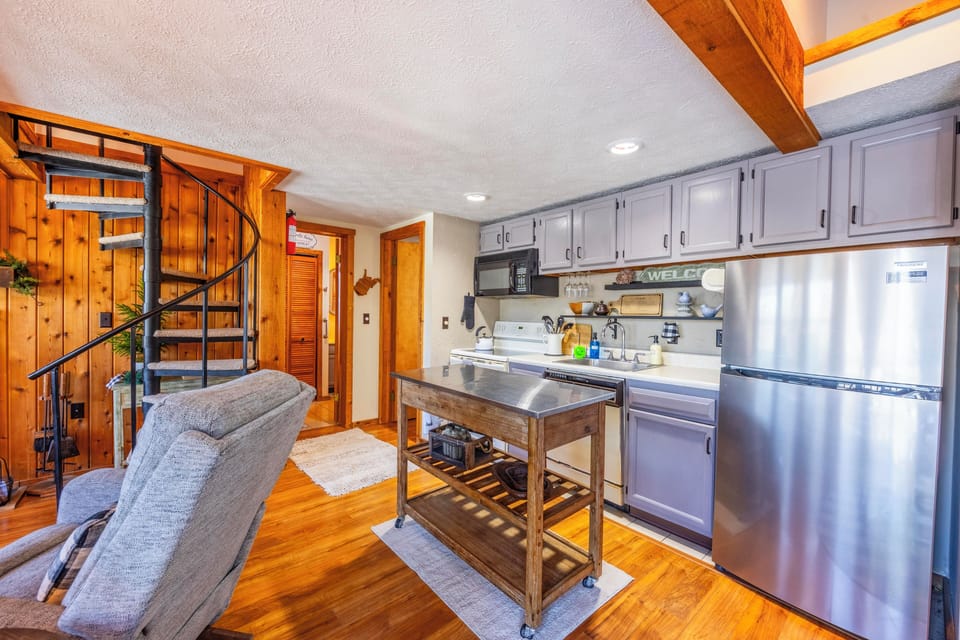 Picture yourself cooking in this charming open kitchen with stainless steel appliances and rustic wood accents. The unique spiral staircase adds character to your cozy mountain retreat.