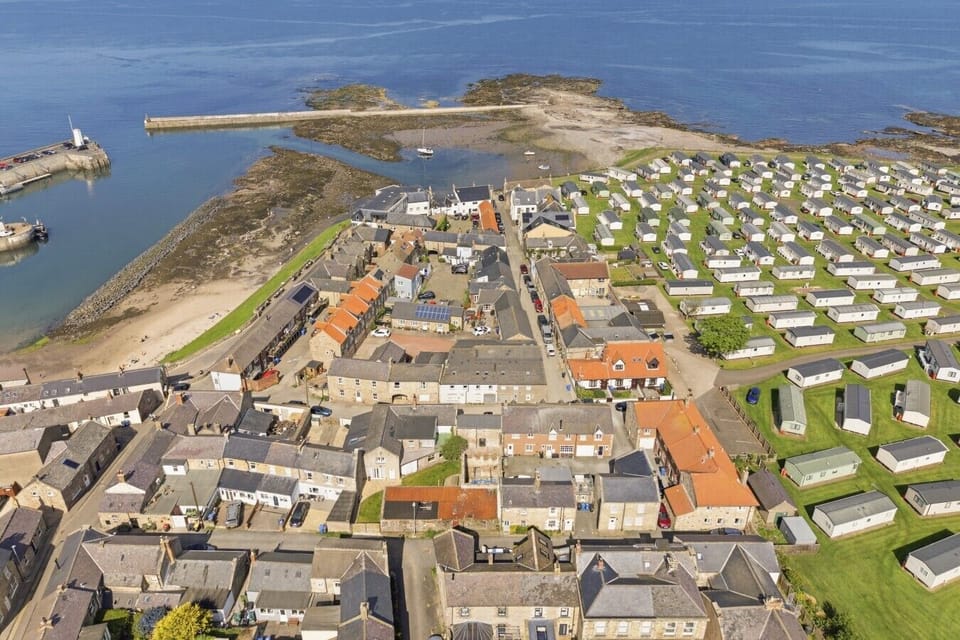 Aerial view of Seahouses harbour, coastline and nearby holiday village.